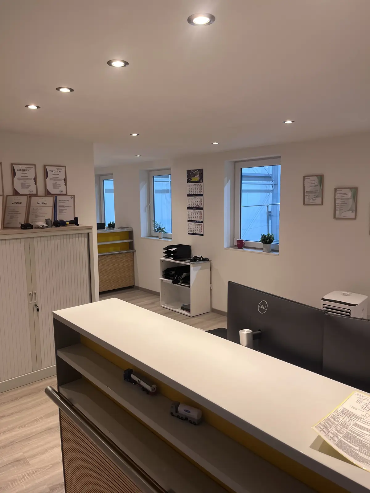 Büro mit Arbeitsplatz, Schränken und Fenstern