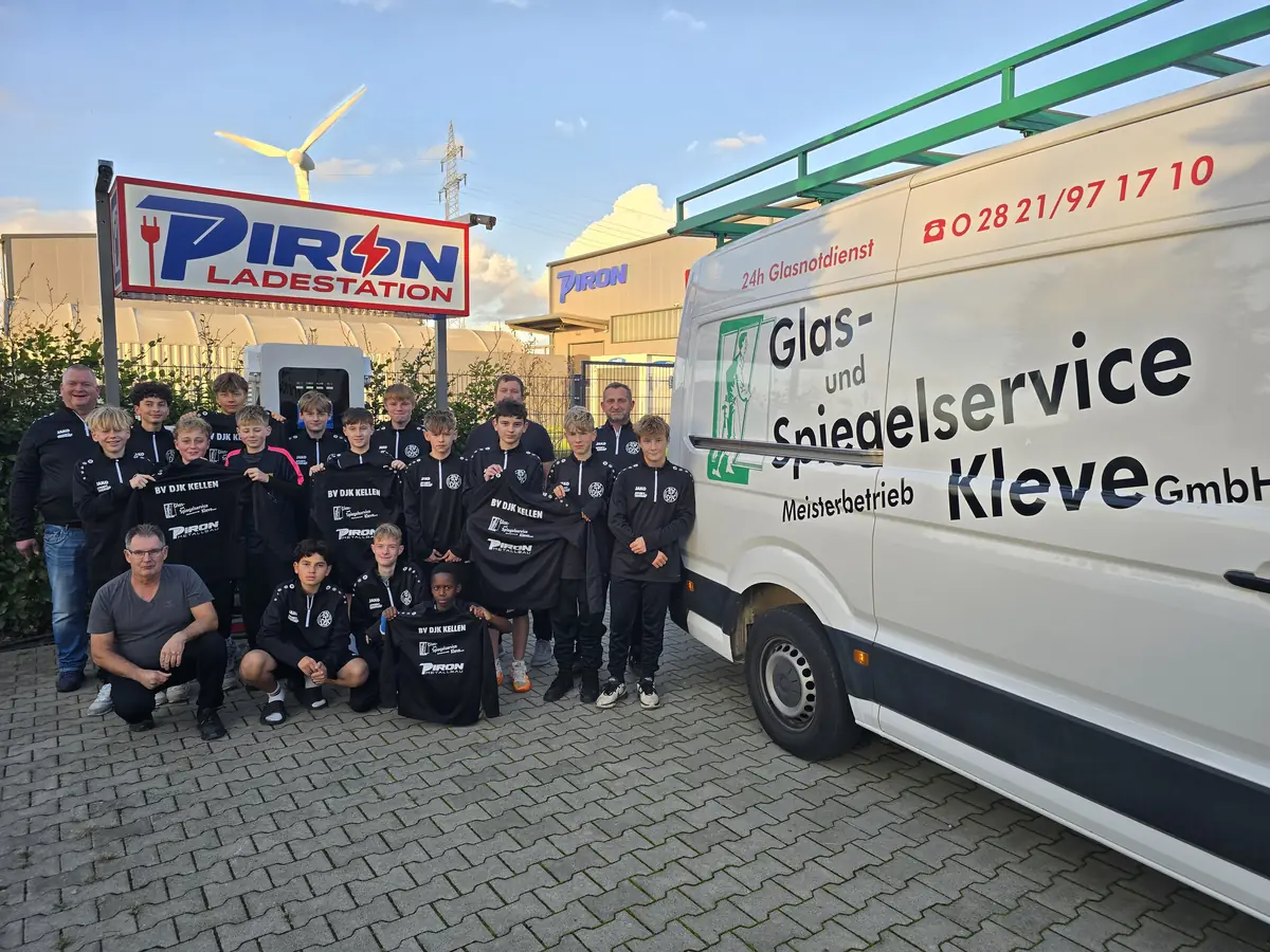 Die C2-Jugend des BV DJK Kellen mit Trainern und Betreuern vor der PIRON Ladestation in Kleve, daneben der Transporter von Glas- und Spiegelservice Kleve