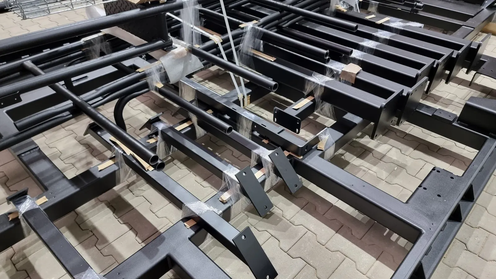 Schwarz lackierte Stahlbauteile mit Anschlussplatten, verpackt zur Auslieferung